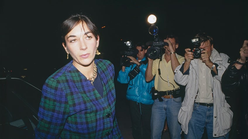 Ghislaine Maxwell wearing a plaid blazer and walking away from photographers.