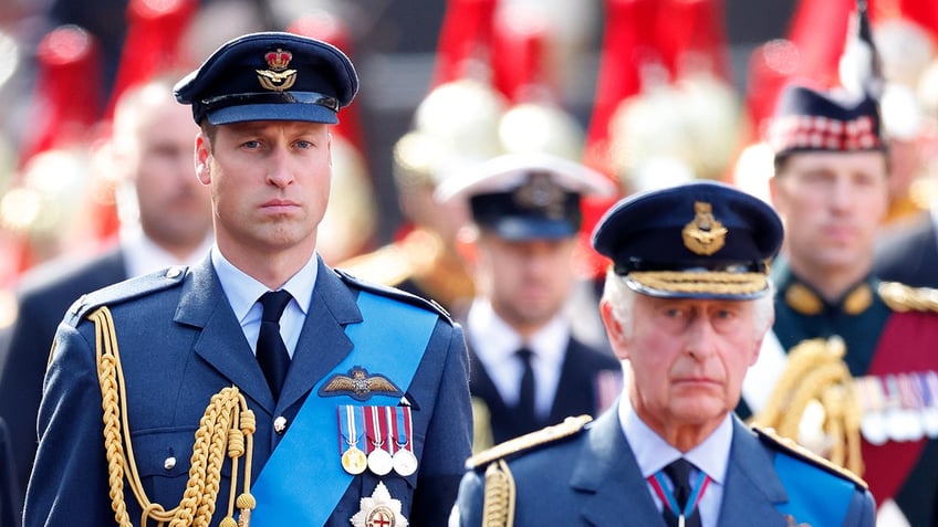 Prince William marching behind his father KIng Charles in uniforms.