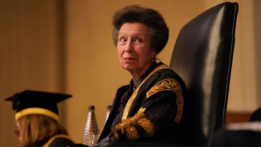 Princess Anne looking up while wearing a black and gold robe.