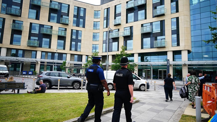 A view of a hospital with two policemen walking towards it.