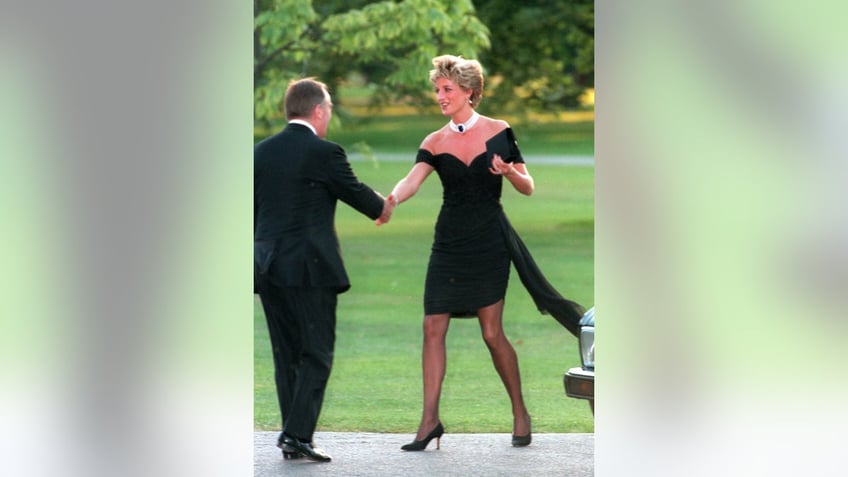 Princess Diana stepping out of the car in her revenge little black dress shaking hands with a man in a suit.