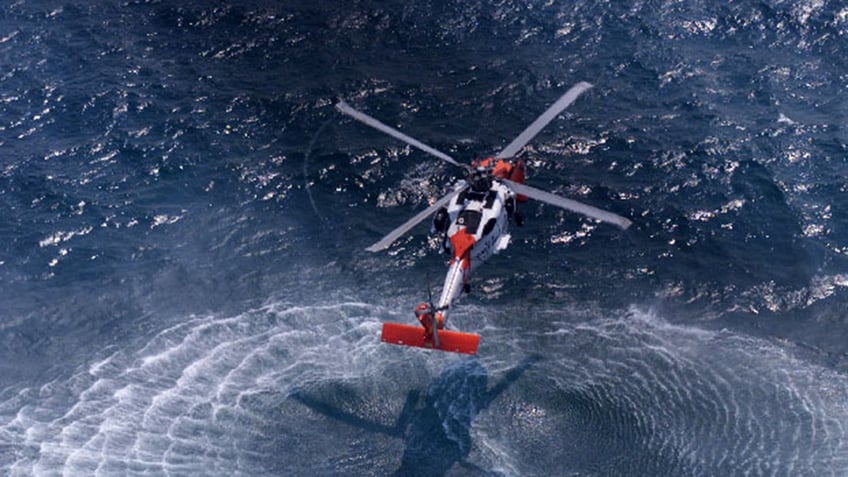 a helicopter hovering over the ocean.