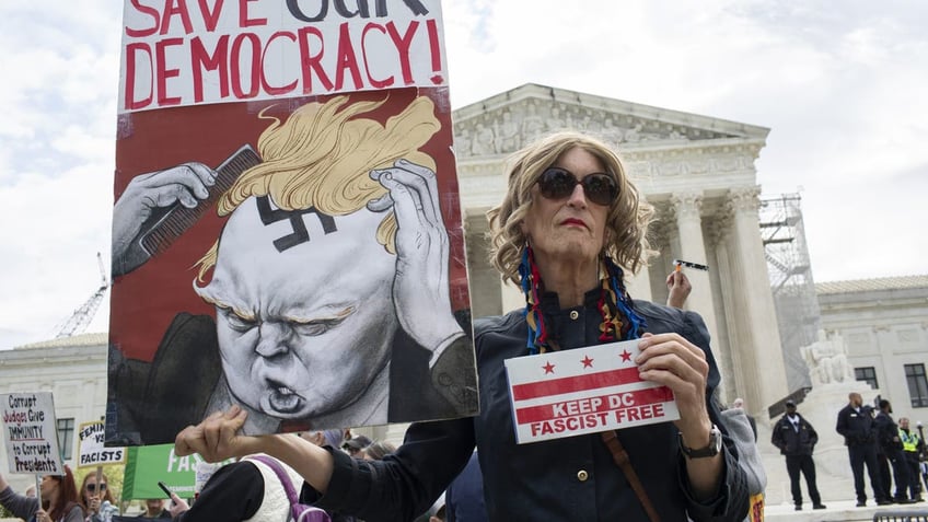 An activist holding a sign with "Save Our Democracy" written on it stands outside the Supreme Court, as the court prepares to hear arguments on the immunity of former President Donald Trump.