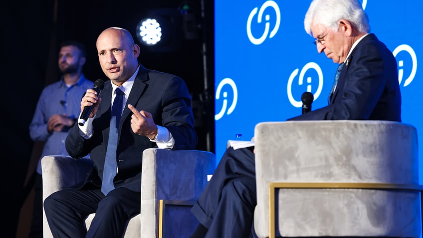 Naftali Bennett holding microphone at summit panel