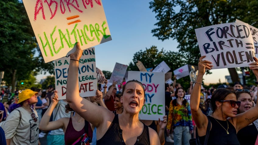 Supreme Court protesters hold signs.