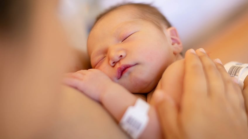 A mother holding her newborn baby on her warm chest at the hospital