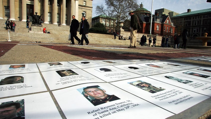 On Veterans Day, a memorial showing names and photos of Americans killed in the wars in Afghanistan and Iraq is viewed by passersby at Columbia University.