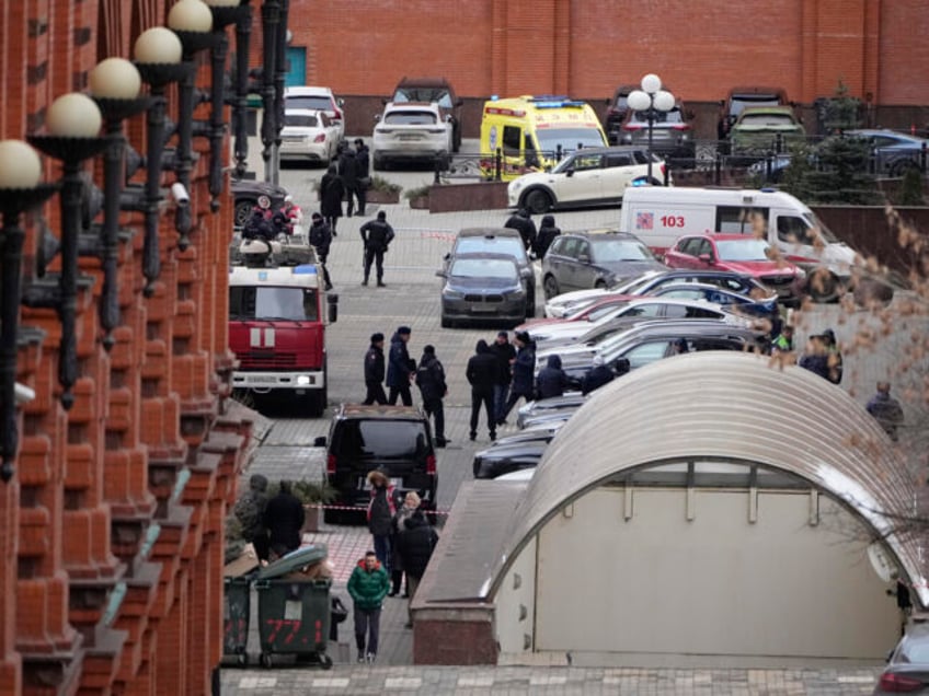 Investigators and police officers stand in the yard of an upscale residential block in Mos