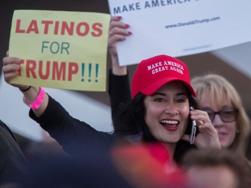 A woman hoods a sign expressing Latino support for Republican presidential candidate Donal