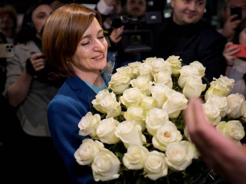 Moldova's President Maia Sandu smiles while holding a bouquet of flowers as she celeb