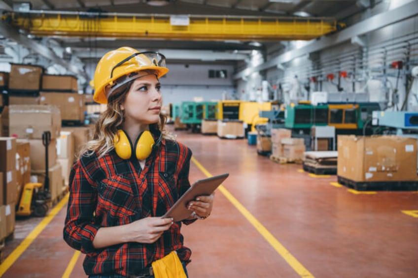 Young maintenance engineer woman in protective clothing using touchpad with digital tablet