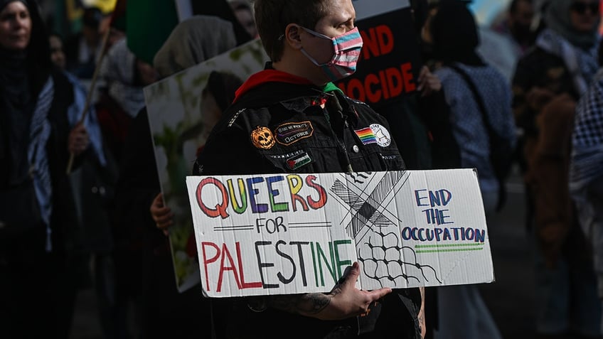 An activist holding a "Queers for Palestine" sign