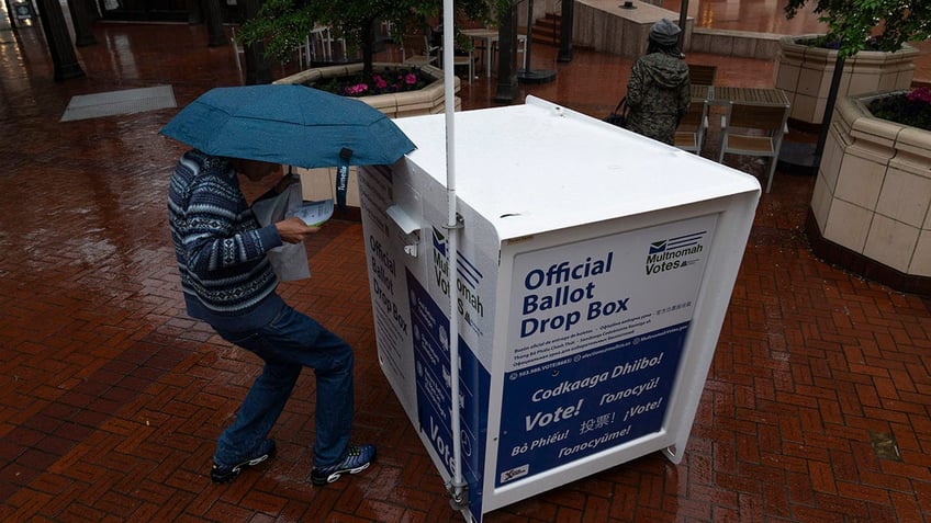 Person drops off their vote-by-mail ballot at a dropbo