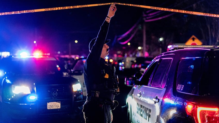 sacramento county sheriffs deputy holds crime scene tape over car