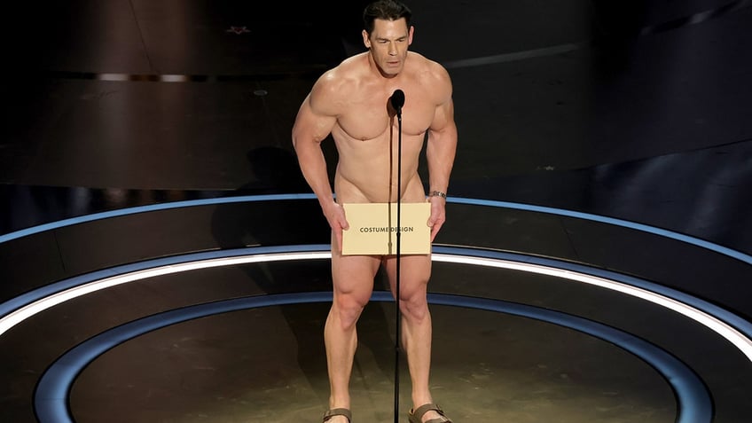 John Cena holds an envelope on stage