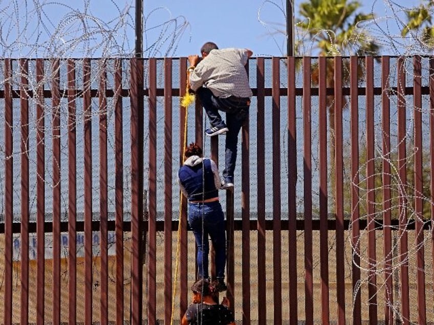 MEXICALI, BAJA CALIFORNIA - MAY 13: Migrants attempt to climb over the border wall from Me