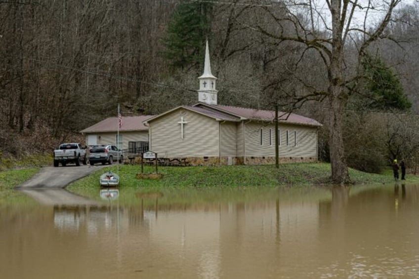 Residents stand on the grounds of Confluence Baptist Church in a heavily flooded neighborh