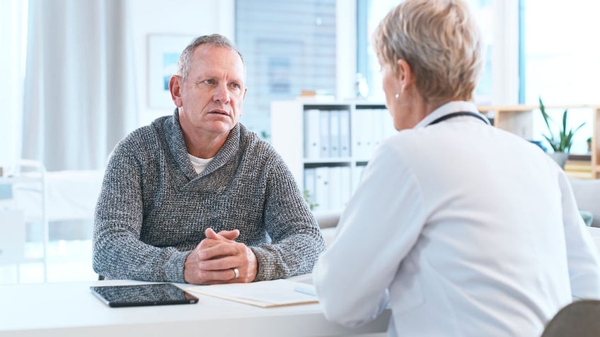 Senior Female Doctor Consulting with Elderly Male Patient in Modern Medical Office