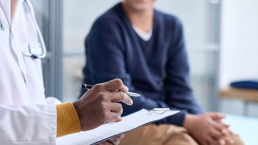 Side view closeup of doctor holding clipboard while with patient