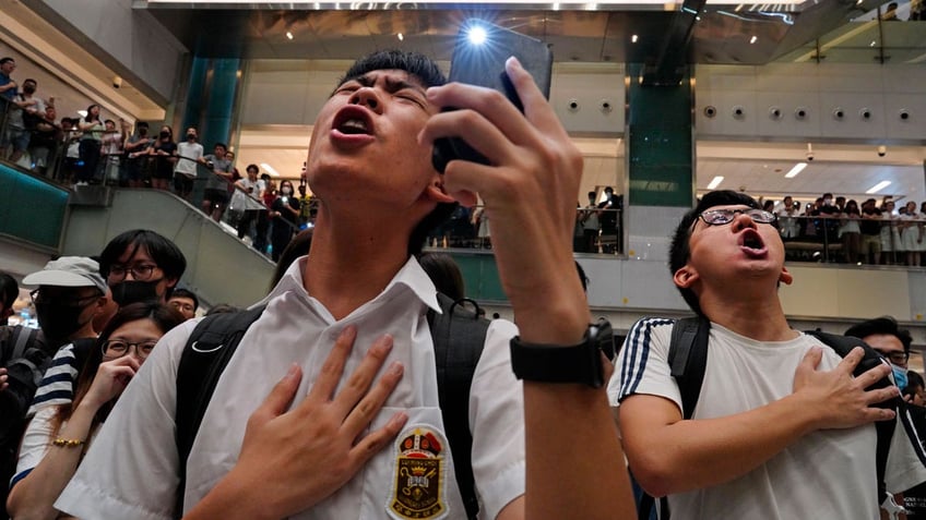 Local residents sing a theme song written by protesters "Glory to Hong Kong" at a shopping mall in Hong Kong