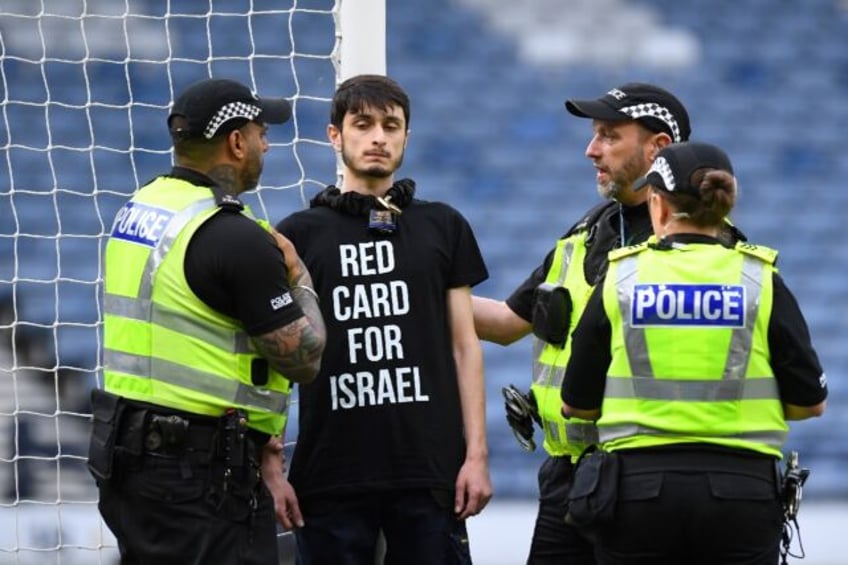 Delay: A demonstrator wearing a T-shirt with the slogan 'Red card for Israel' chained hims