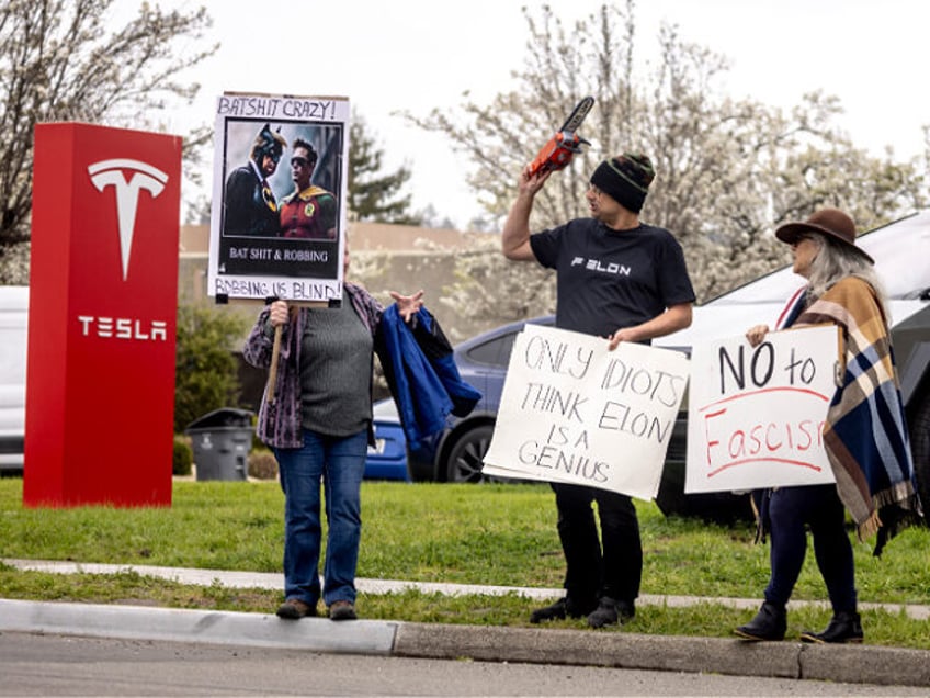 Protesters rally during a protest outside a Tesla showroom against U.S. President Donald T