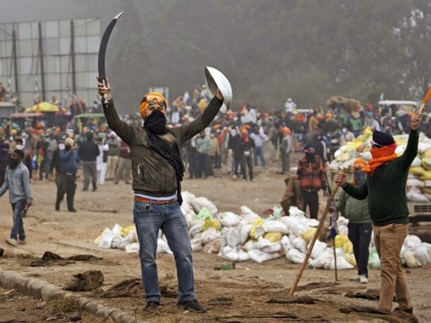 A protesting Sikh farmer carries a ceremonial sword and a shield as farmers clash with the