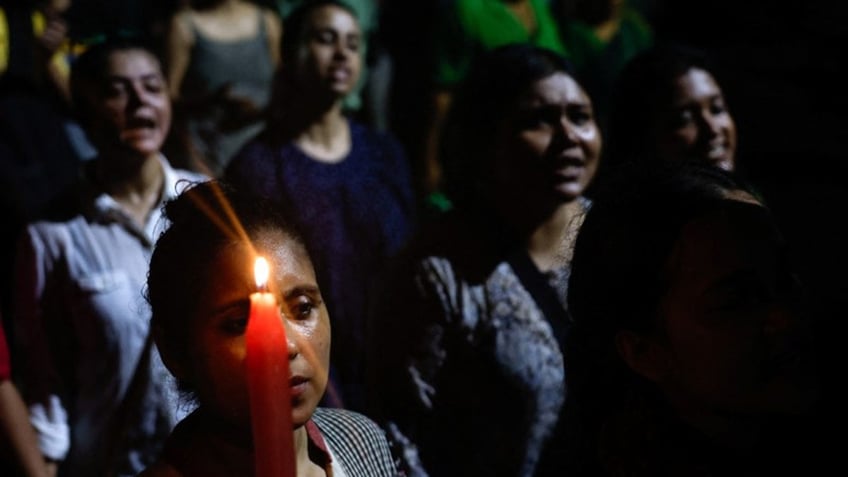 A woman holds a candle as she attends a candlelight vigil condemning the rape and murder of a trainee medic at a government-run hospital in Kolkata