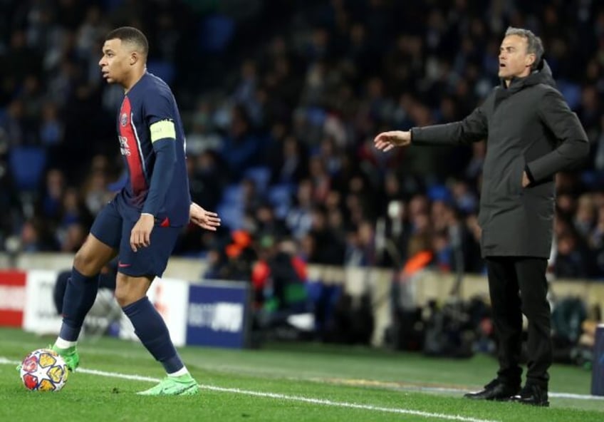 Luis Enrique (R) standing behind Kylian Mbappe (L) during PSG's Champions League last 16 s