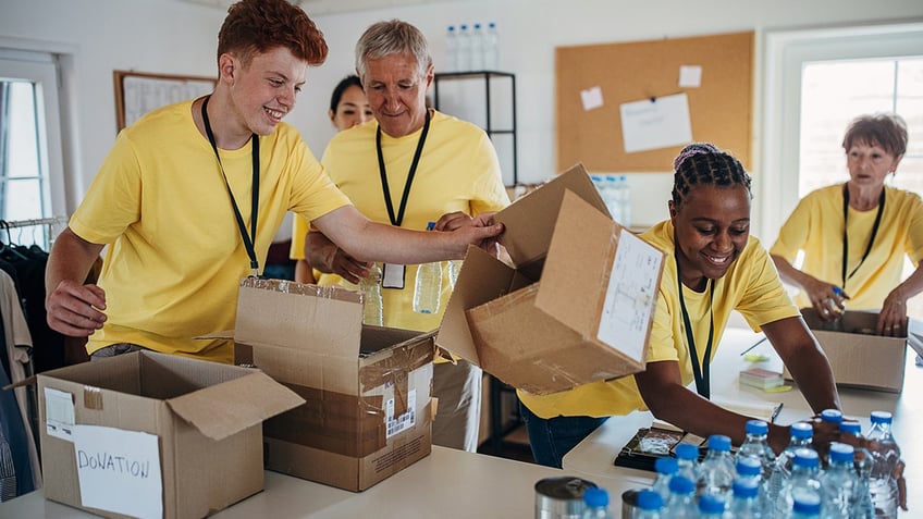 volunteers sorting donated canned food and water bottles into cardboard boxes at charity center