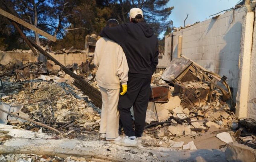 Kyle Kucharski hugs his partner Nicole Perri as they stand on the ruins of their house in