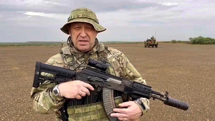 Prigozhin in military fatigues holding a weapon