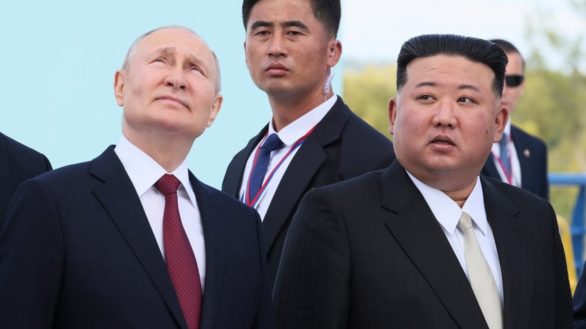 Russian President Vladimir Putin, left, and North Korea's leader Kim Jong Un, right look up at a launch pad of Soyuz rockets.