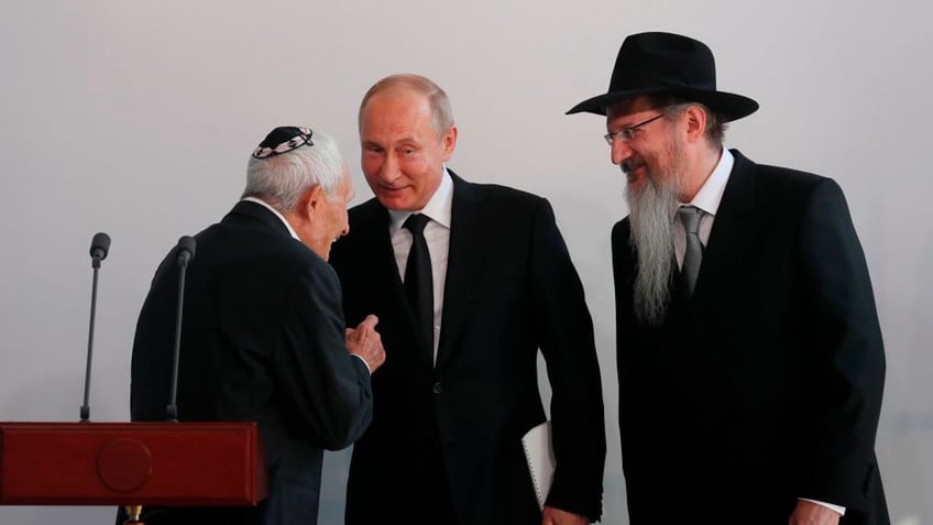 Russian President Vladimir Putin, center, and Chief Rabbi of Russia Berel Lazar, right, attend a ceremony unveiling the memorial for members of the resistance in Nazi concentration camps during World War II at the Jewish Museum and Tolerance Center in Moscow on June 4, 2019.