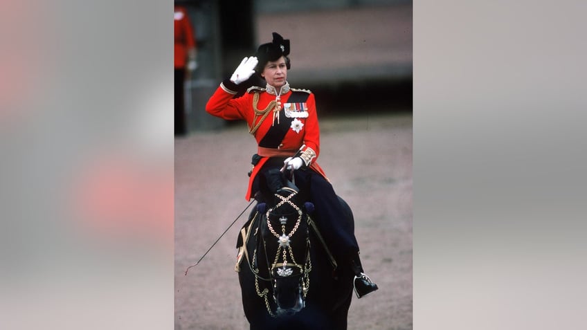 Queen Elizabeth in a red coat riding a black horse