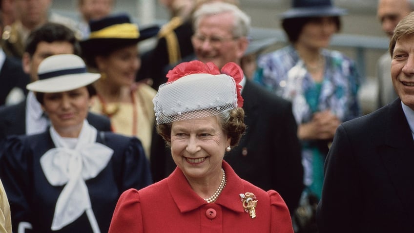 Queen Elizabeth smiling in a red coat.