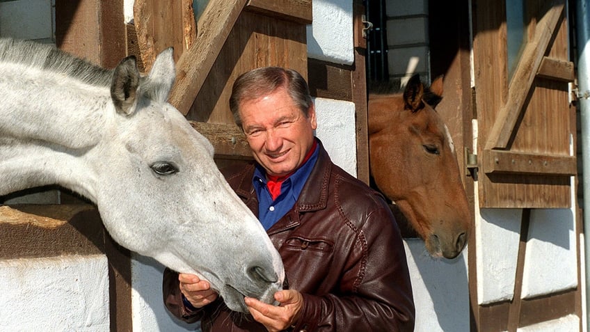 Monty Roberts caressing the face of a horse.