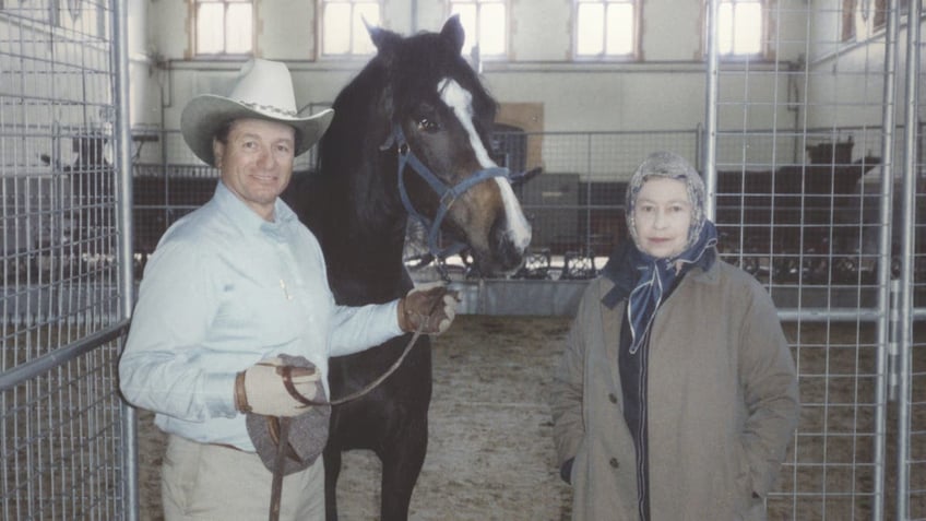 Monty Roberts in cowboy clothes standing next to a horse and Queen Elizabeth II