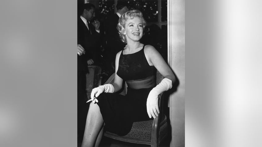 Marilyn Monroe wearing a sheer black dress and holding a cigarette.