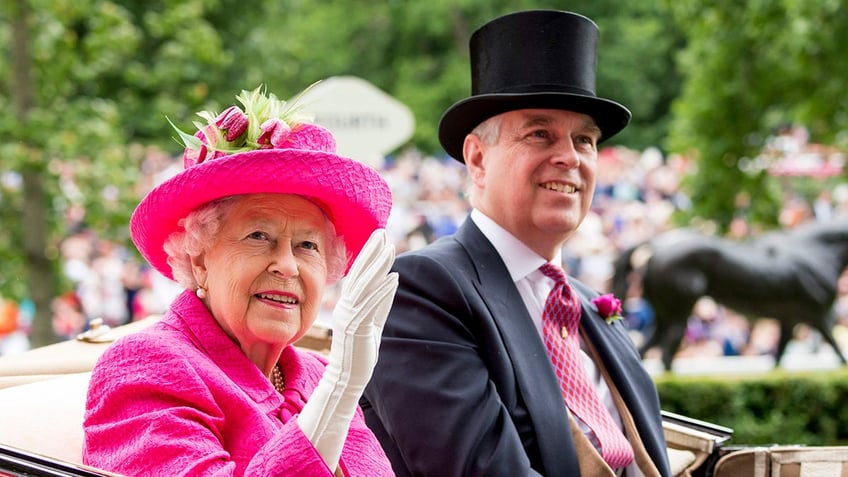 Queen Elizabeth in a hot pink suit waving next to Prince Andrew wearing a suit and top hat on a royal carriage.