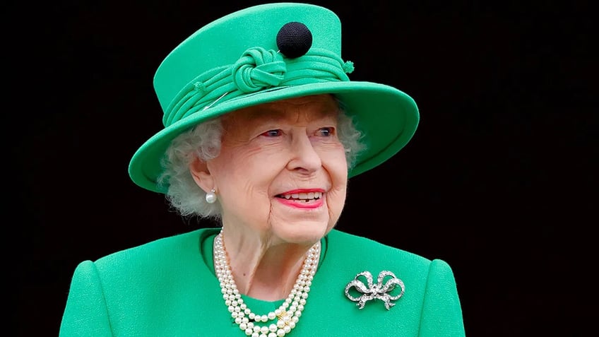 A close-up of Queen Elizabeth wearing a green suit with a matching hat.