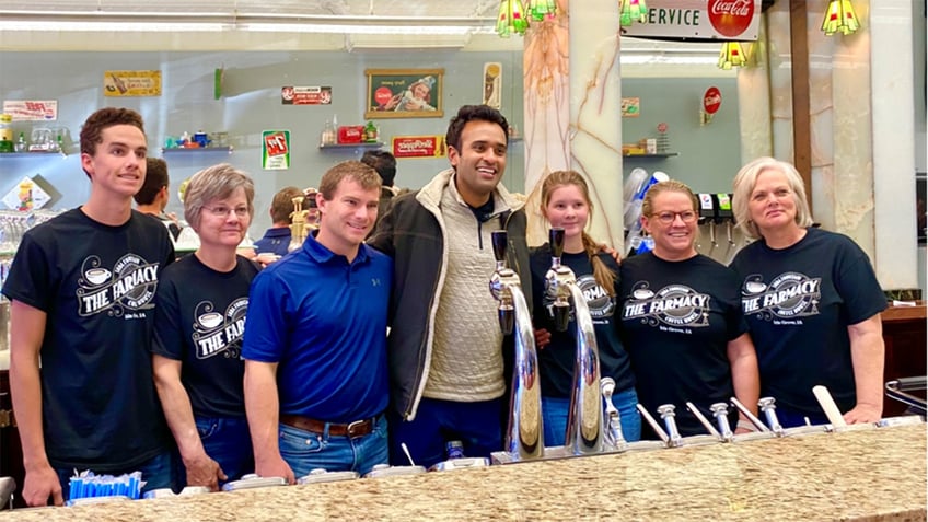 Vivek Ramaswamy in the center with arms around supporters in Iowa smiling