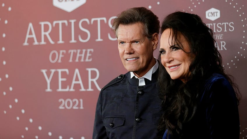 Randy Travis and Mary Travis side angle posing on the red carpet