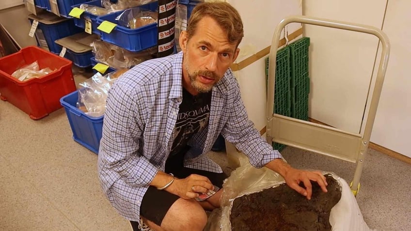 Archaeologist Harvard Hegdal next to an ancient iron gauntlet