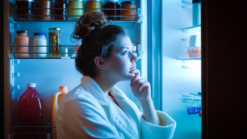 A woman standing in front of the refrigerator