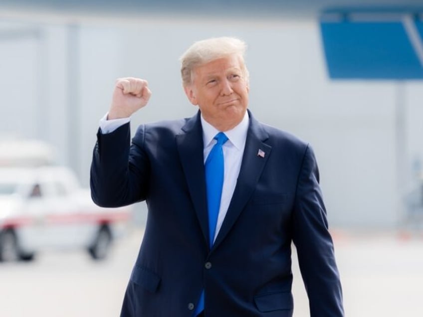 President Donald J. Trump gestures with a fist pump as he walks across the tarmac upon his