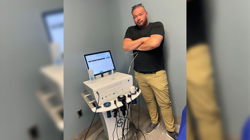 Jon Gosselin crosses arms next to cellsound treatment machine.