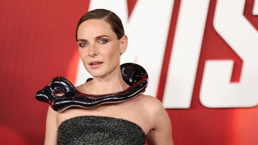 Rebecca Ferguson on the carpet in a black strapless gown with a snake-like piece wrapping around her neck