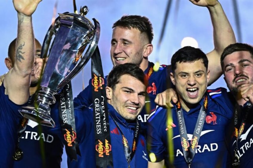 Antoine Dupont (C) holds the Six Nations trophy next to France's winger Louis Bielle-Biarr