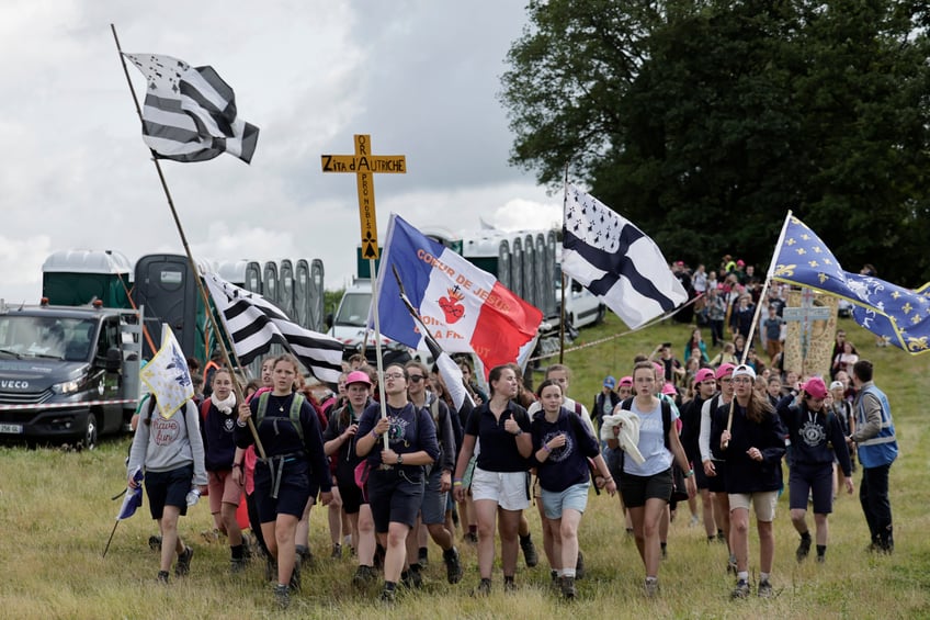 Pelgrins hold crosses, banners and flags as they arrive for the Mass, during the traditional Pentecostal pilgrimage from Paris to Chartres, in Sonchamp, near Paris, on June 8, 2025. From the church of Saint-Sulpice in Paris, thousands of people began their march towards Chartres on June 7, 2025 for the great traditionalist pilgrimage, which is attracting a record 19,000 Catholics this year, despite certain tensions with the episcopate. (Photo by STEPHANE DE SAKUTIN / AFP) (Photo by STEPHANE DE SAKUTIN/AFP via Getty Images)